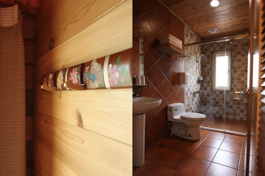 A wooden interior with a tiled bathroom including a shower, toilet, and sink.