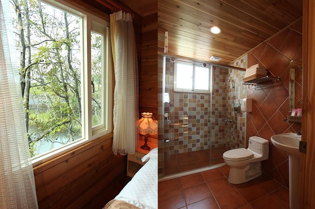 A wooden cabin with a large window, a shower, and a toilet.