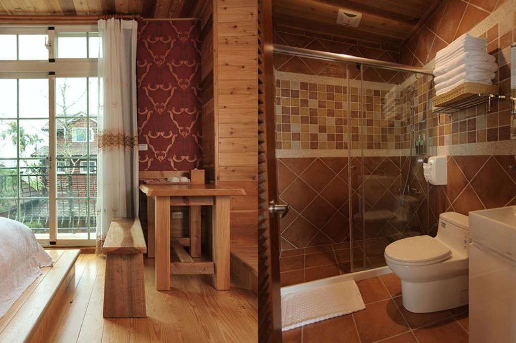 A wooden cabin with a bedroom, a small wooden table, a bench, a shower with a glass door, and a toilet.