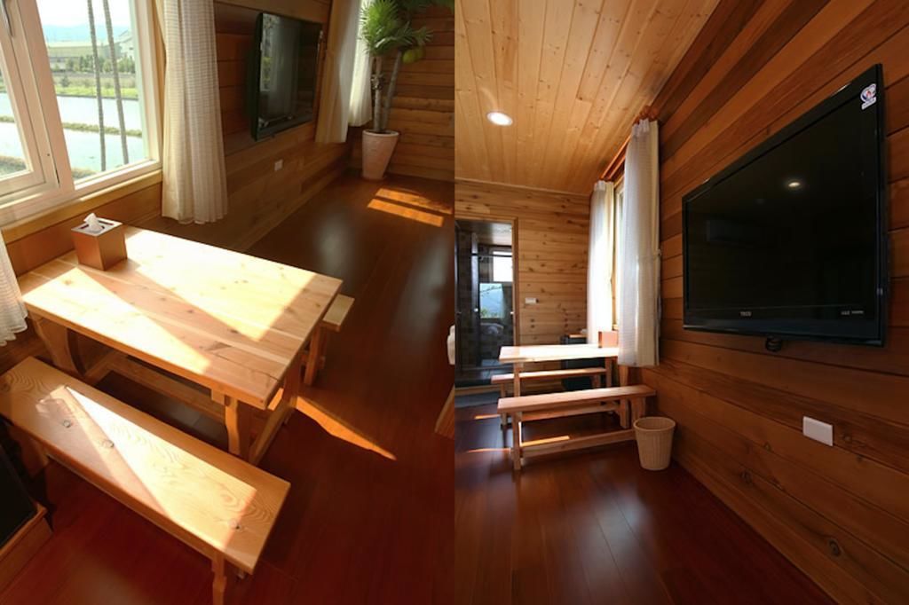 L’intérieur d’un chalet en bois, avec une table à manger, des bancs, un téléviseur et une plante en pot.