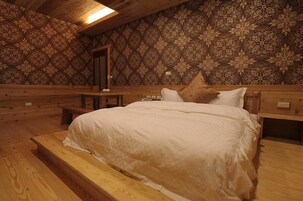 Una habitación tipo cabaña de madera con una cama, bancos y un papel tapiz estampado.