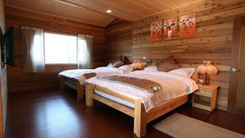 A wooden cabin bedroom with two beds, a window with curtains, and a wall-mounted artwork.