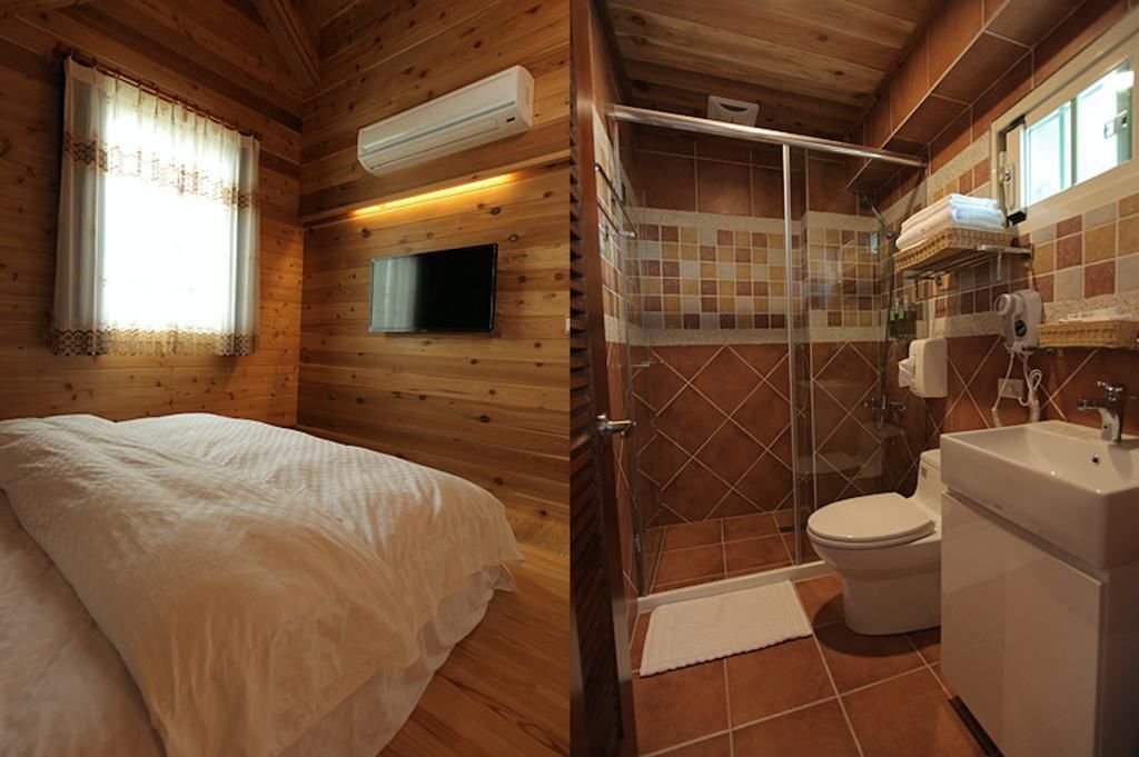 A wooden cabin bedroom with a bed, a TV, and a shower area with a glass door.