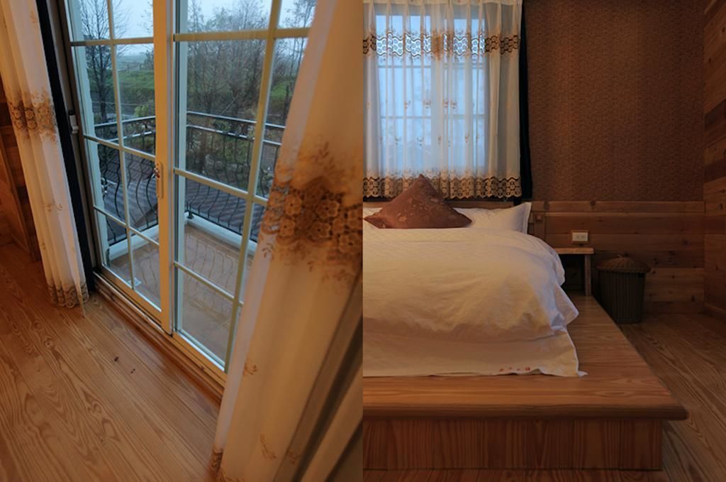 A wooden room with a bed, a window with a view of a garden, and a wooden bench.