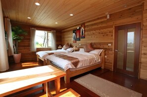 A wooden cabin bedroom with two beds, a bench, and a door. - North Zart Homestay (Dongshan)