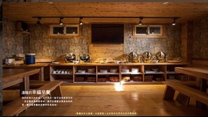Um interior rústico de madeira, com paredes de pedra, prateleiras de madeira e uma mesa central com diversos pratos e utensílios.