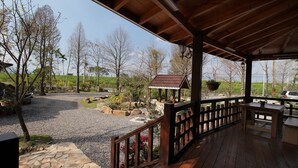 Uma área externa coberta com um deck de madeira, um caminho de pedra e um pequeno jardim com pedras e plantas.