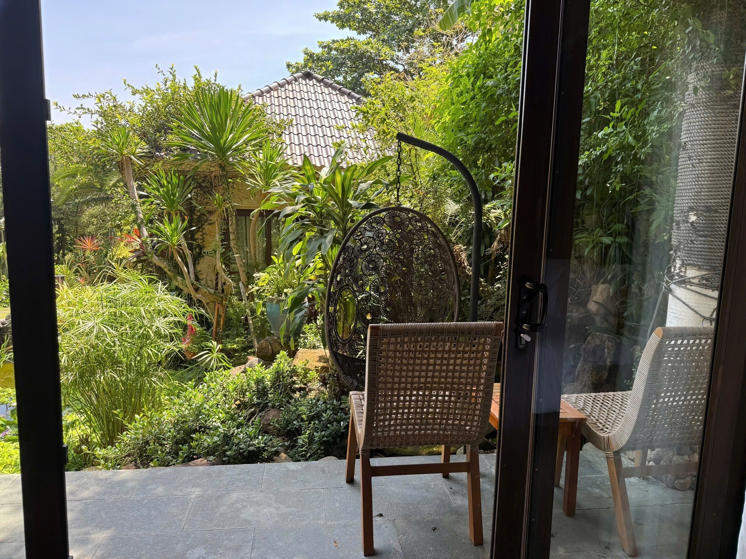 A garden view with a wicker chair and a decorative metal gate.