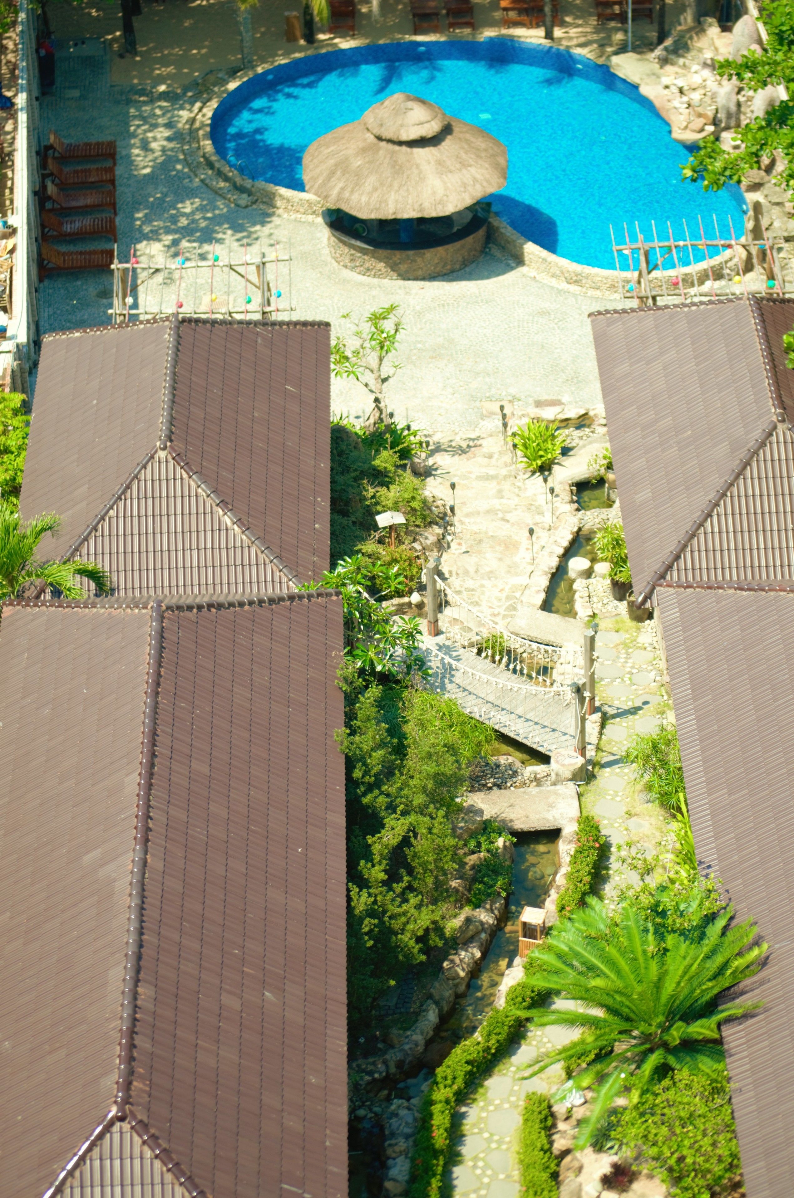 Un complexe hôtelier doté d’une piscine, de bâtiments à toits de chaume et d’un sentier en pierre.