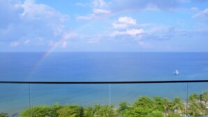 Vista del océano con un arcoíris y un barco a lo lejos.