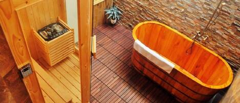 A wooden sauna room with a wooden bathtub, a wooden bench, and a small wooden chest.