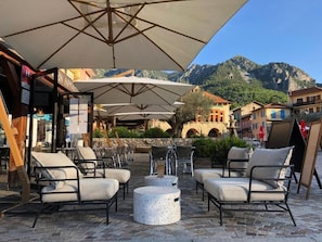 Un espace extérieur aménagé avec des chaises et des tables, des parasols, et un paysage montagneux en toile de fond.