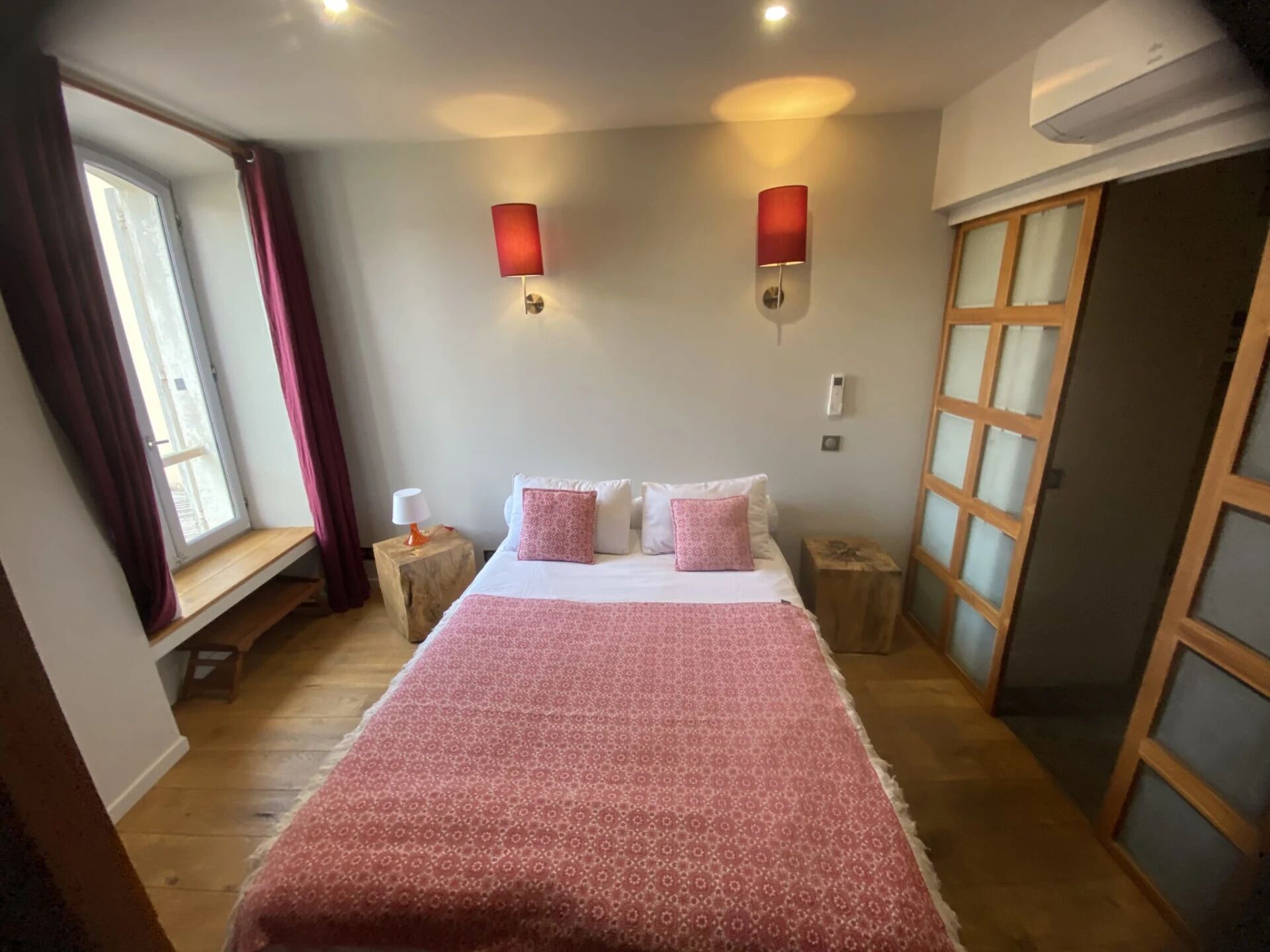 Un dormitorio con una cama grande, dos mesitas de noche, una ventana con cortinas y un armario de madera.
