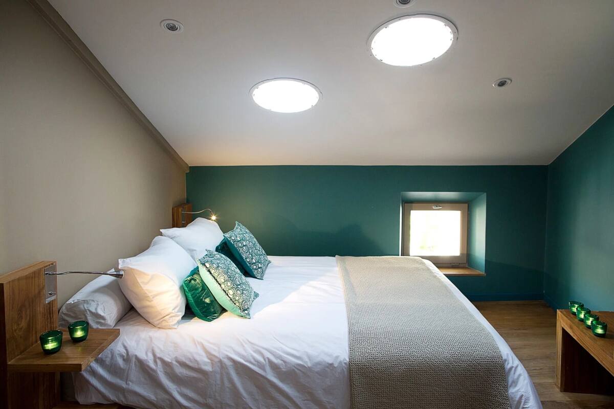 Ein Schlafzimmer mit einem Bett, Nachttischen, einem Fenster und einem Oberlicht.
