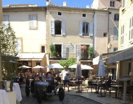 A cobblestone street with outdoor seating, a vintage car, and a building with a sign reading "Galerie du Temple".