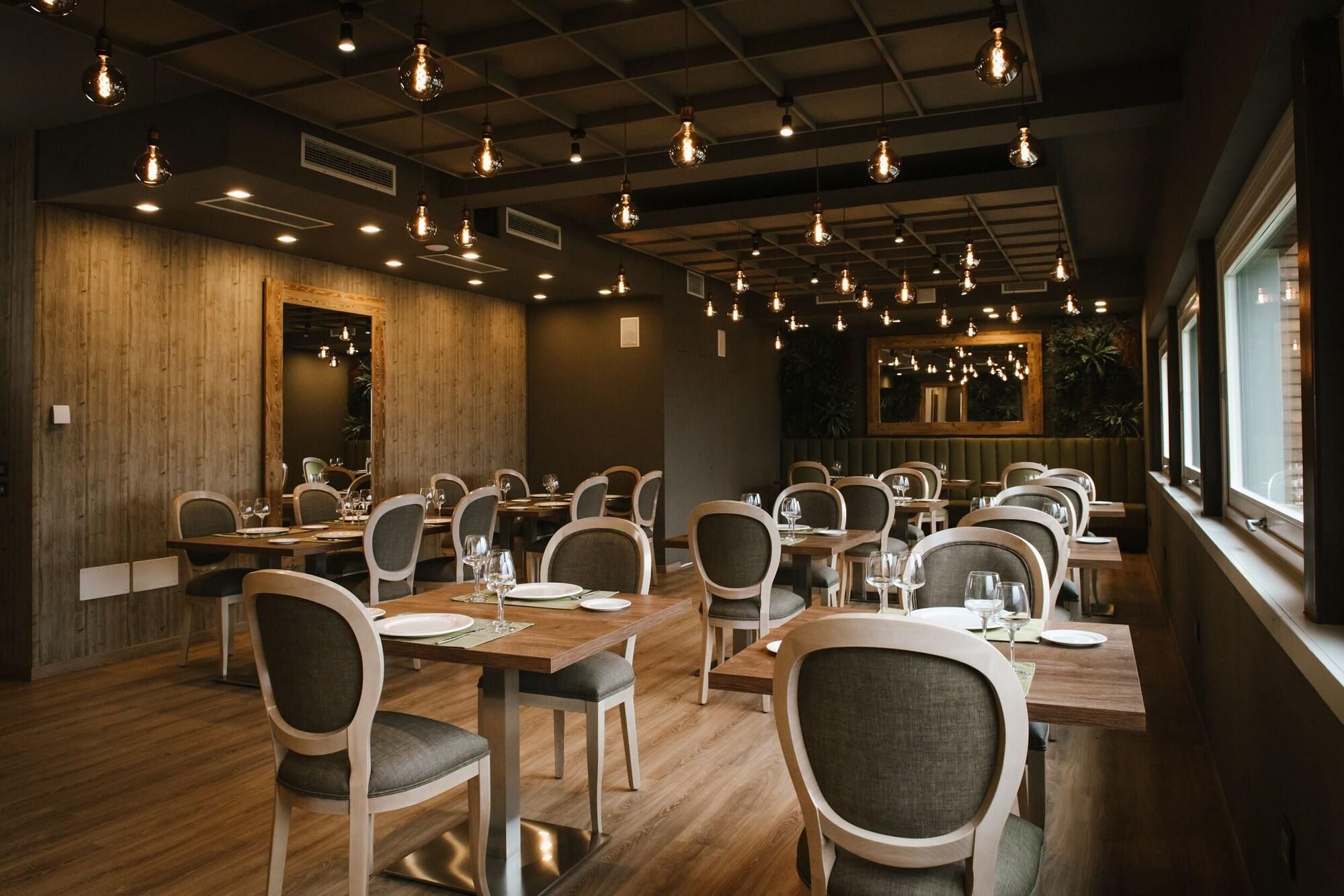 A restaurant with wooden walls, multiple tables, and hanging light fixtures.