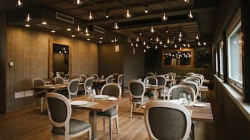 A restaurant with wooden walls, multiple tables, and hanging light fixtures.