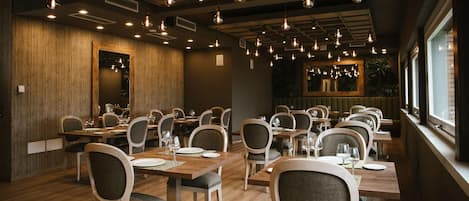 A restaurant with wooden walls, multiple tables, and hanging light fixtures.