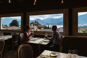A restaurant with large windows offering a view of mountains and a lake. - Lake Hotel La Pieve (Pisogne)