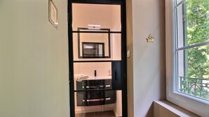 Un baño con mampara de vidrio, un lavamanos y un espejo.