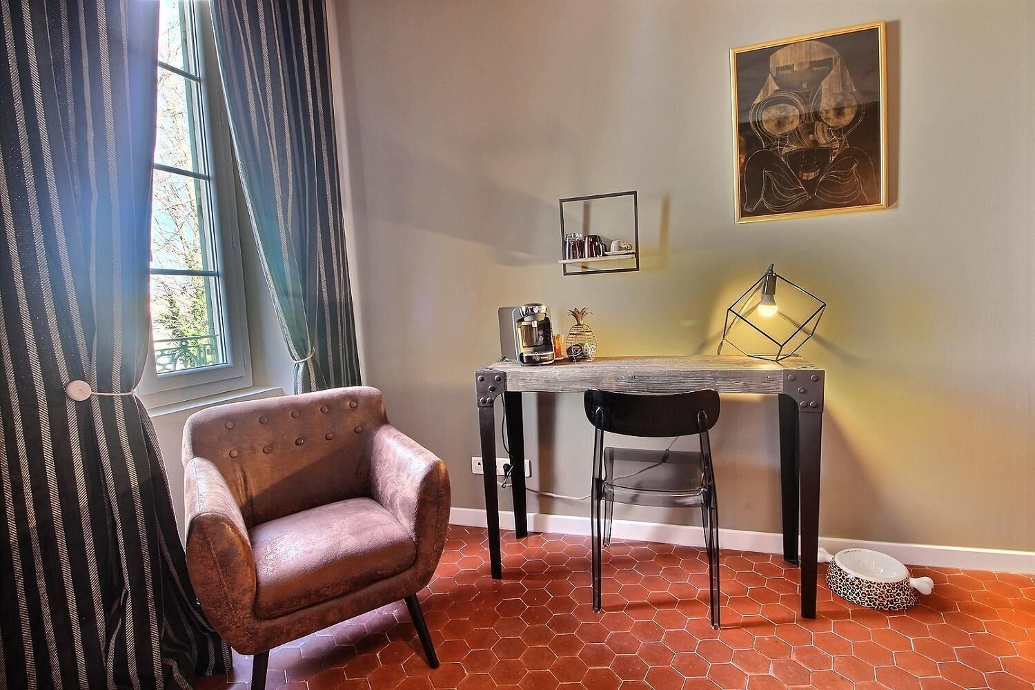 Un comedor con una mesa, sillas, una cafetera y un cuadro en la pared.