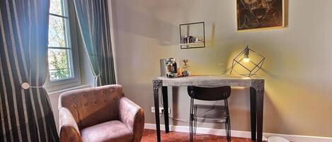 Un comedor con una mesa, sillas, una cafetera y un cuadro en la pared.