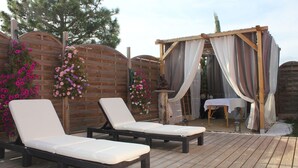 A wooden deck with two lounge chairs and a pergola with draped fabric. - Résidence Cala Corsa (Lecci)