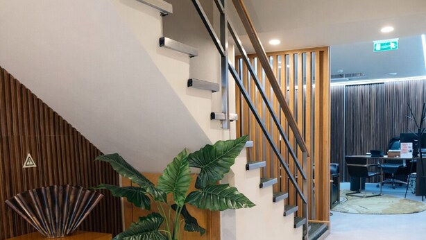 A modern interior with a wooden staircase, a potted plant, and a wooden shelf with decorative items. - Hotel Zenite (Angra do Heroismo)
