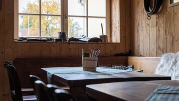 A wooden interior with a window, a table, chairs, and a bench.