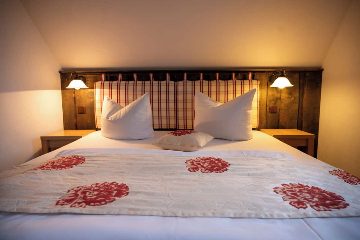 Een net opgemaakt bed met een bloemenbedekker, twee kussens en een hoofdbord met verticale strepen.