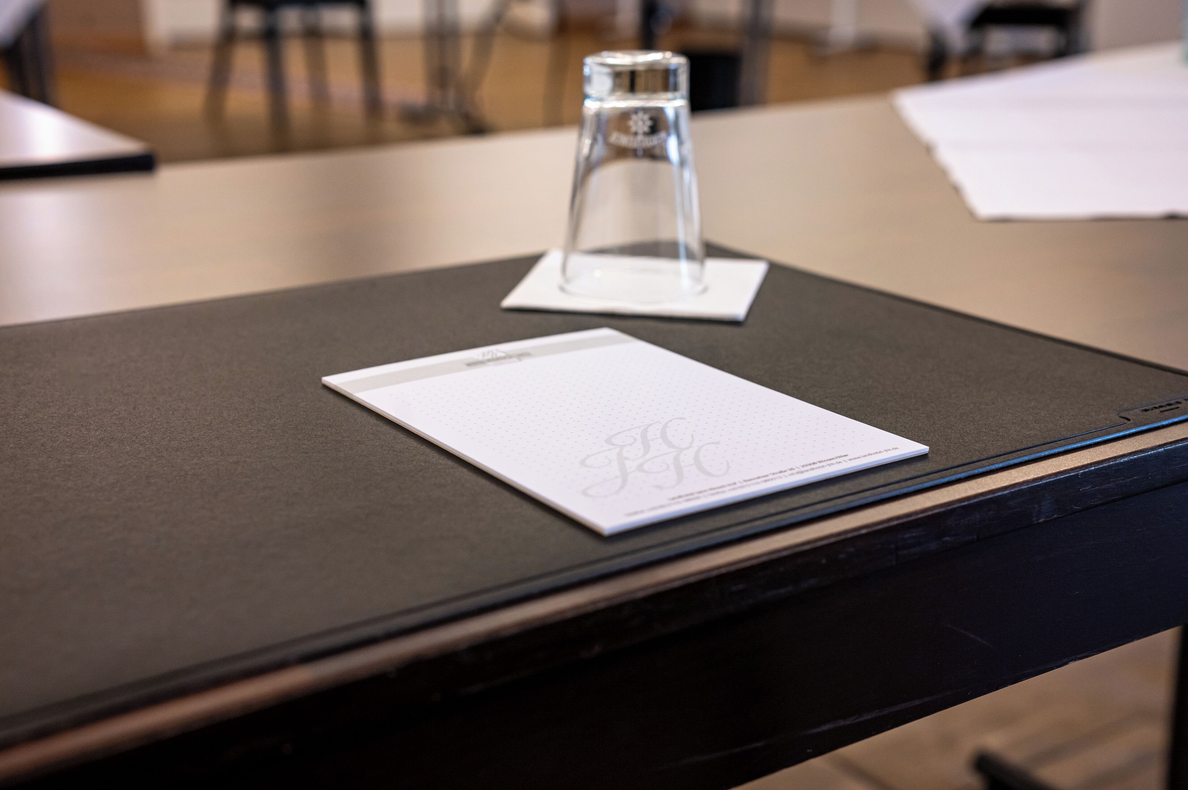 Una mesa con un objeto de vidrio transparente y un papel blanco con un logotipo.