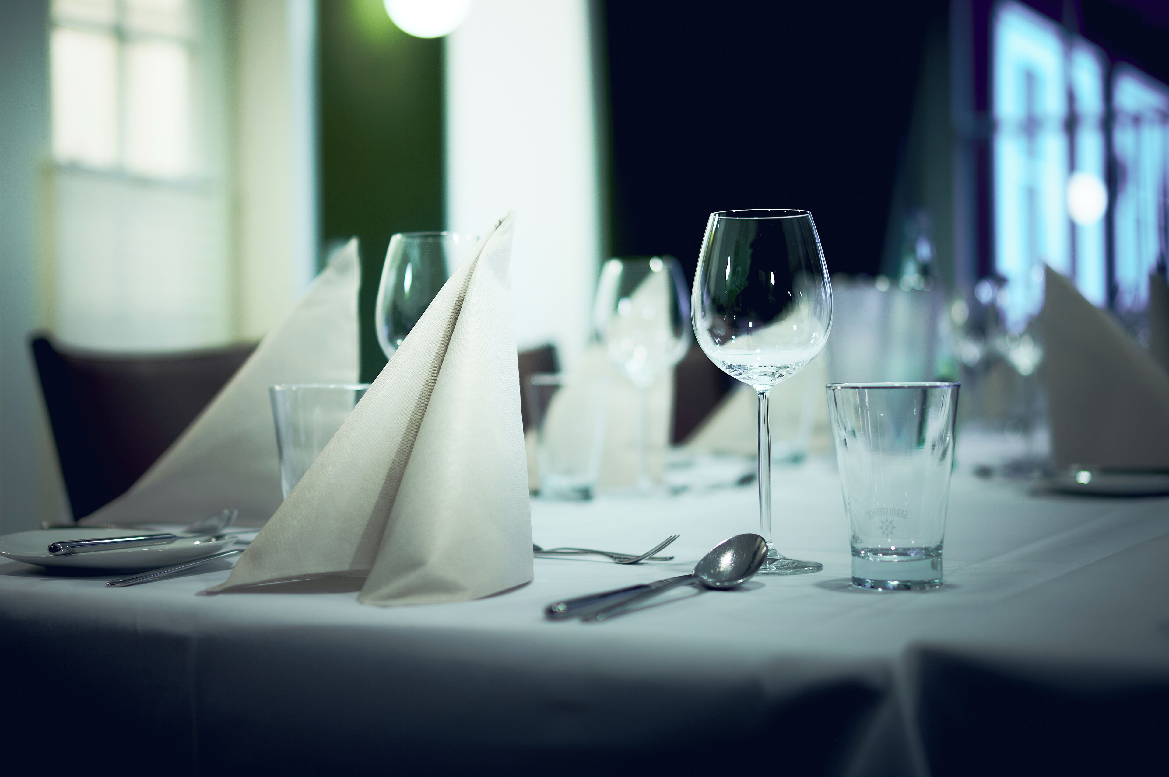 A dining table set with wine glasses, a spoon, and a napkin.