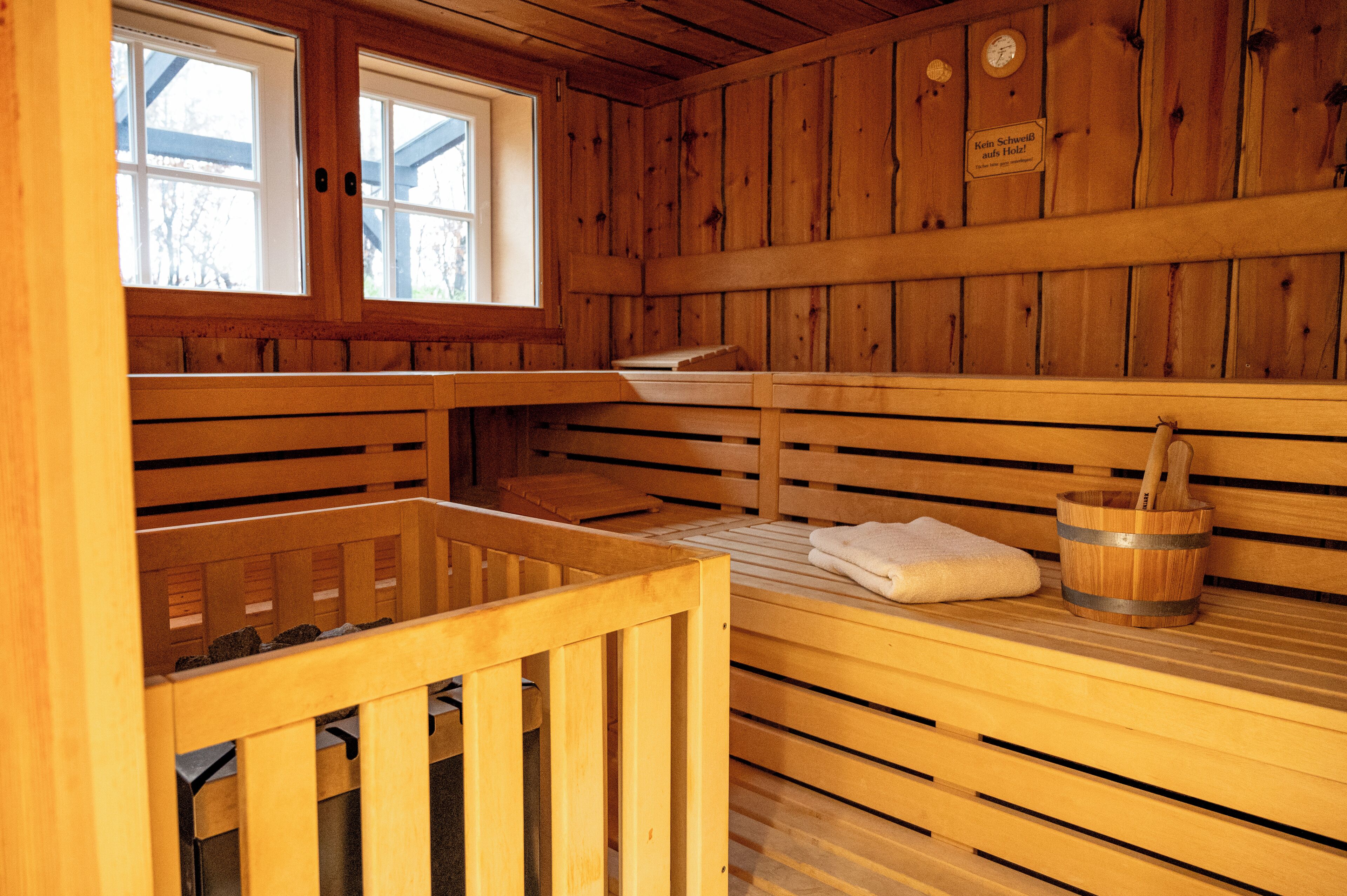 Una sauna de madera con bancos, un balde de madera y una toalla.