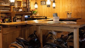 Een houten bar met hangende lampen, een bar en lederen accessoires.