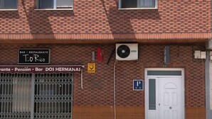 A brick building with two air conditioning units, a sign for 'Bar Restaurante Too Rico', and a 'P' parking sign.
