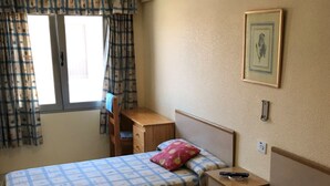 A bedroom with two beds, a desk, and an air conditioning unit.