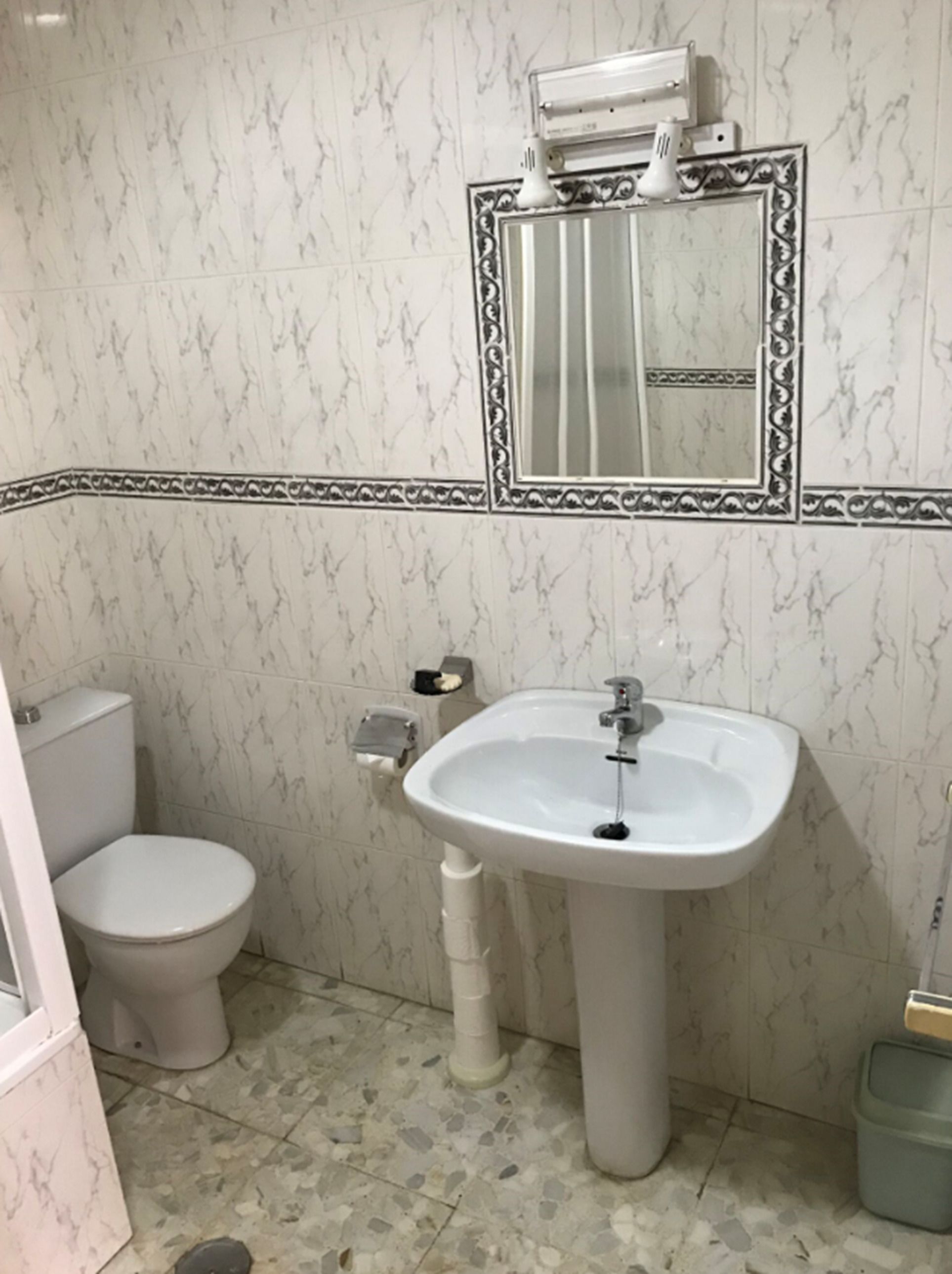 Une salle de bain avec des toilettes, un lavabo et un miroir.