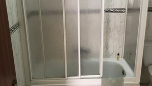 A bathroom with a glass-enclosed shower, a toilet, and a bathtub.