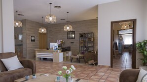 A modern living room with a wooden coffee table, two brown sofas, and a reception desk with a computer and decorative items. - Pradaria Asador y Alojamiento (Arcas del Villar)