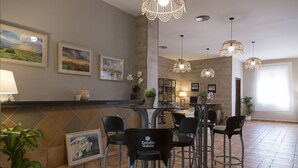 A restaurant with a bar area, multiple hanging light fixtures, and framed artwork on the walls. - Pradaria Asador y Alojamiento (Arcas del Villar)