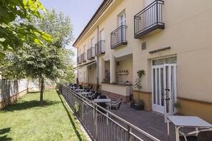 Un edificio con mesas al aire libre, un árbol y una puerta con panel de vidrio.