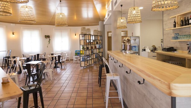 A restaurant interior with wooden ceiling, hanging wicker lamps, white chairs, and a bar area. - Pradaria Asador y Alojamiento (Arcas del Villar)