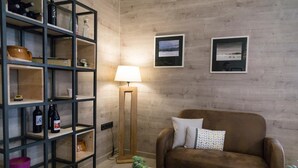 A living room with a brown sofa, a coffee table, a floor lamp, a bookshelf, and two framed pictures on the wall. - Pradaria Asador y Alojamiento (Arcas del Villar)