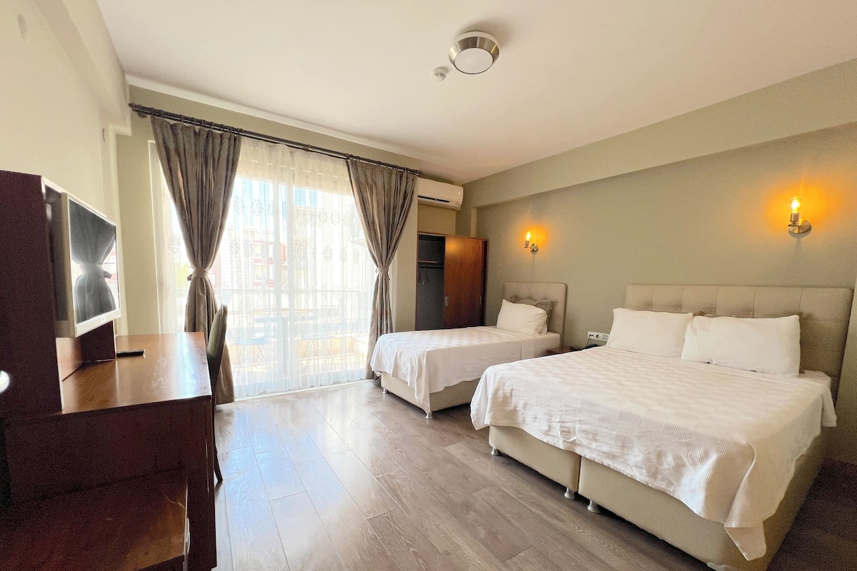 Habitación de hotel con dos camas, un escritorio y un televisor.