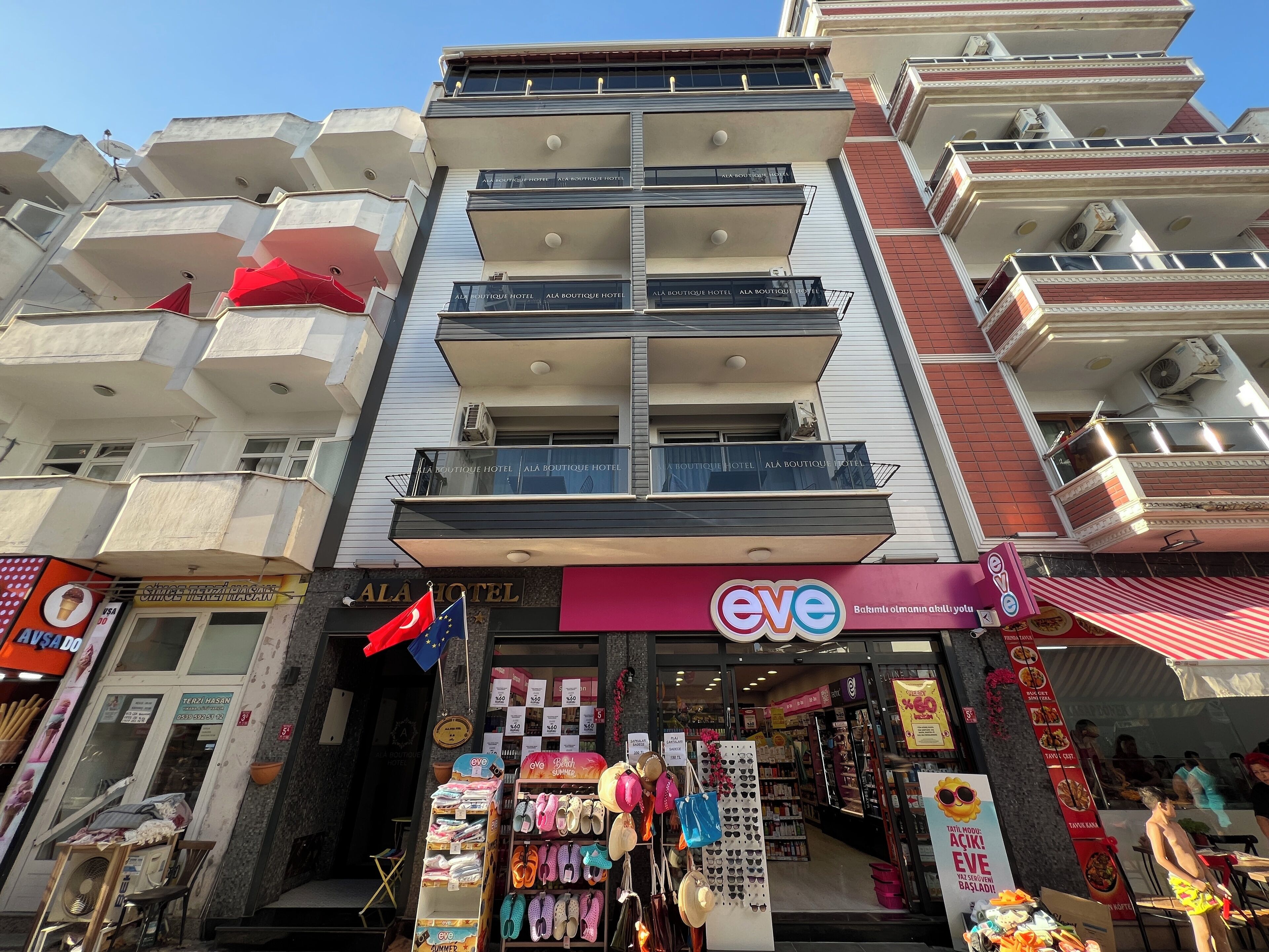 Un edificio de varios pisos con balcones, una fachada para el 'Ala Boutique Hotel' y una tienda llamada 'eve' que vende calzado.