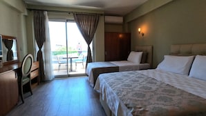 Habitación de hotel con dos camas, un escritorio con espejo, un armario y una puerta corrediza de vidrio que da a un espacio exterior.