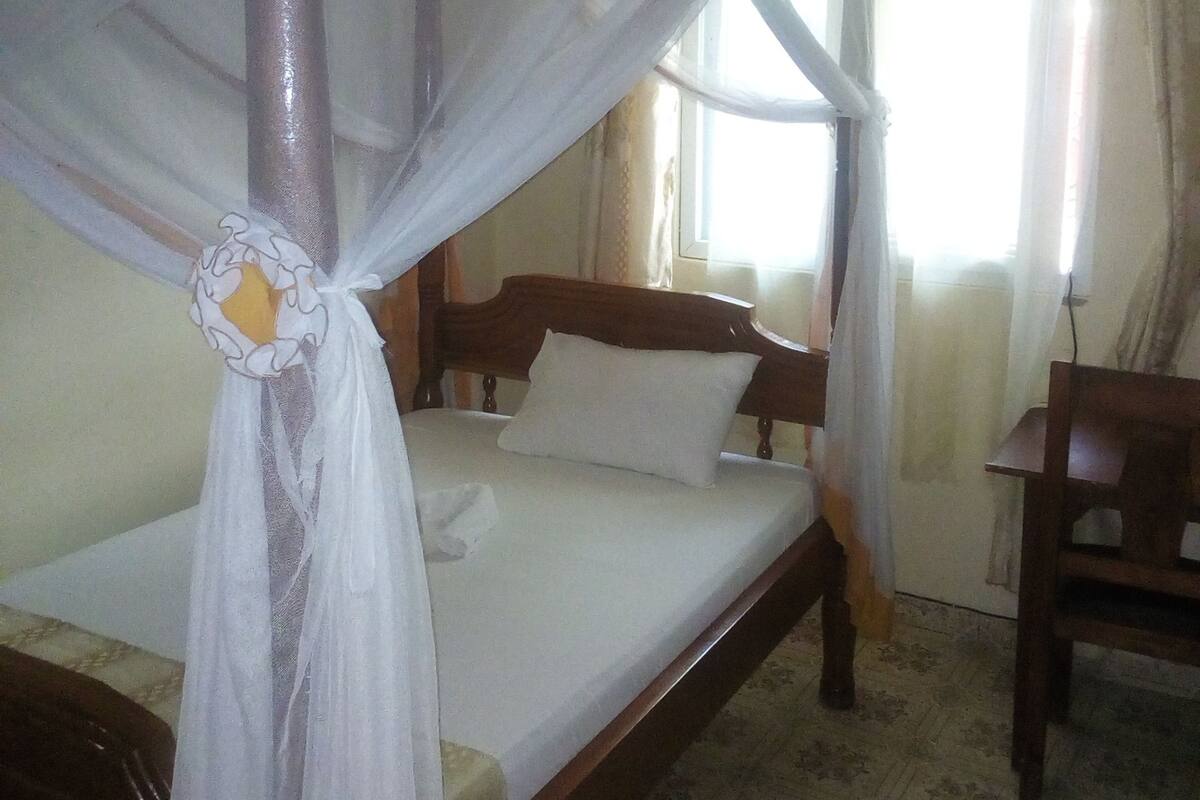 A bed with a canopy, a wooden headboard, and a nightstand.