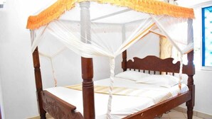 Un lit à baldaquin avec des poteaux aux quatre coins, une structure en bois et du linge de lit blanc.