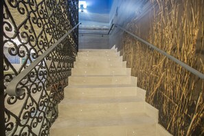 A staircase with a metal railing and a wall with a textured pattern. - Hotel Barrio Nuevo (Lebrija)