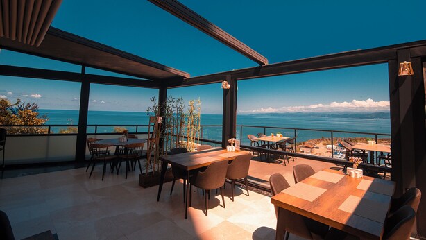 Una terraza con mesas y sillas con vistas a un hermoso paisaje marino.